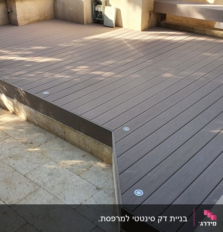 דק עץ חום עם ברגים על רצפת אבן